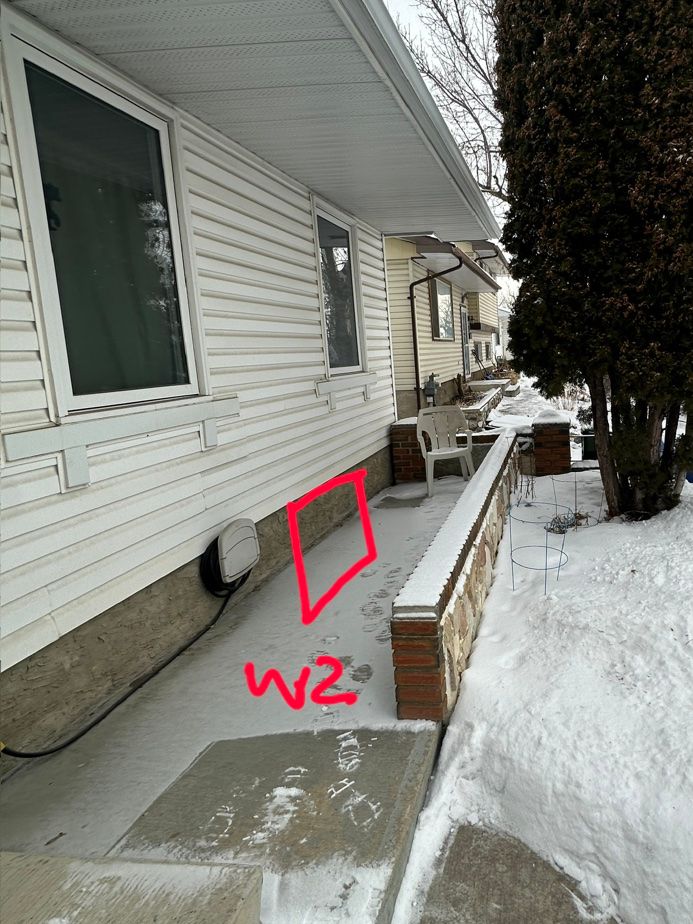 Example planning photo, not completed work: the outside side wall of a house with the proposed basement window spot marked in red.