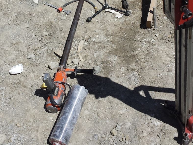 Concrete drilling equipment beside a foundation work area.