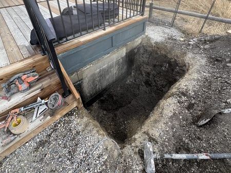 Excavation beside a deck for a basement window opening.